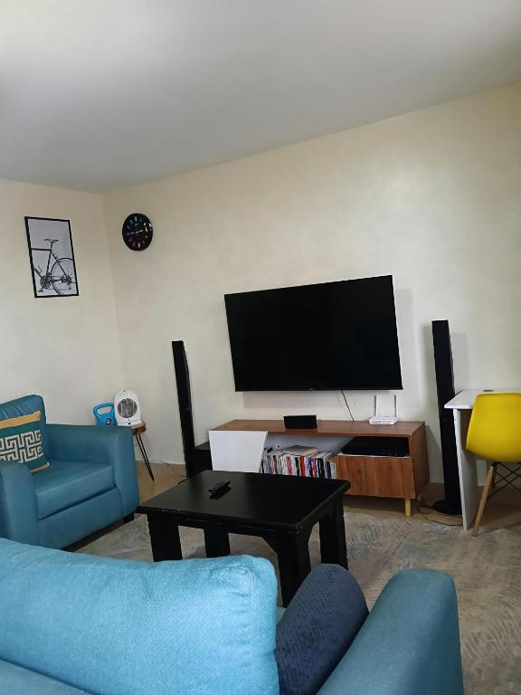a living room with a blue couch and a tv at Classy bedroom Ngong in Ngong
