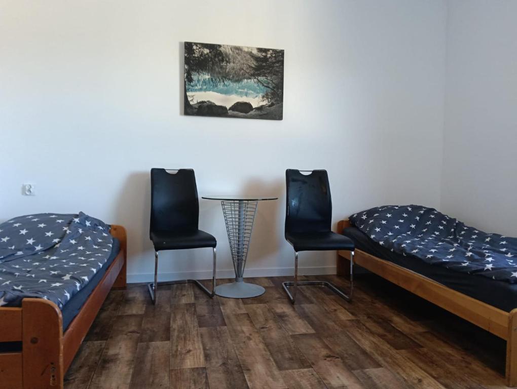 two beds and two chairs in a room at Noclegi Adam in Radonia