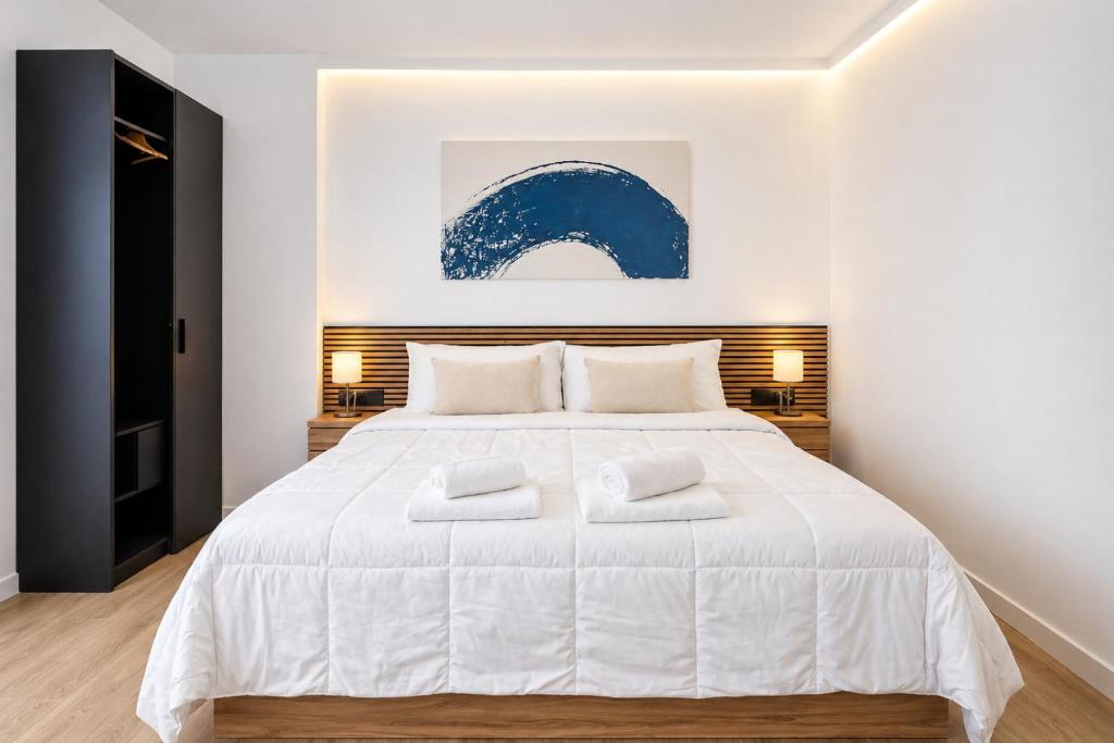 a bedroom with a large white bed with two white towels at Prime Suites Valencia in Valencia