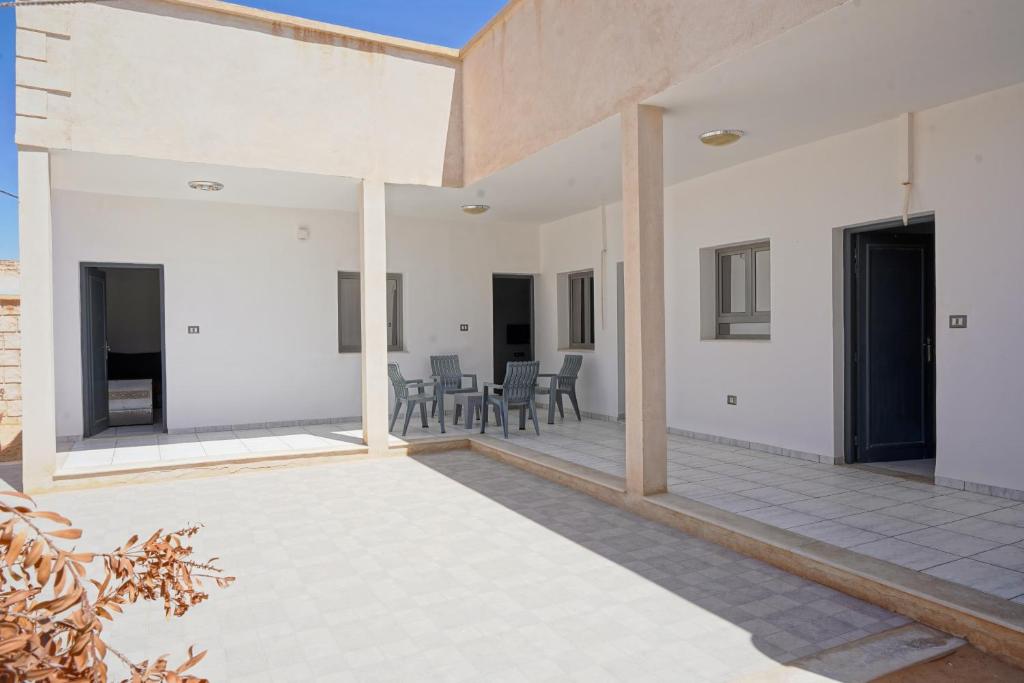 an outdoor patio with white walls and tables and chairs at BBS Maison in Douz