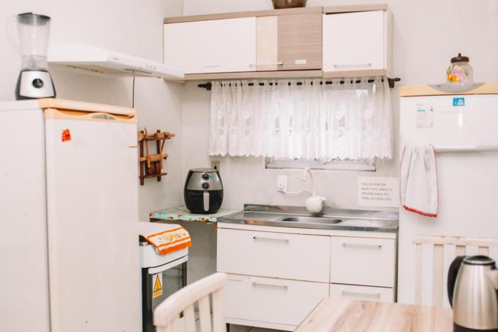 a kitchen with white cabinets and a refrigerator at Hostel Uziel in Timbó