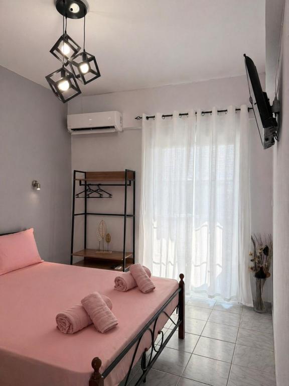 a bedroom with a pink bed and a window at Matinas rooms in Nea Mesangala