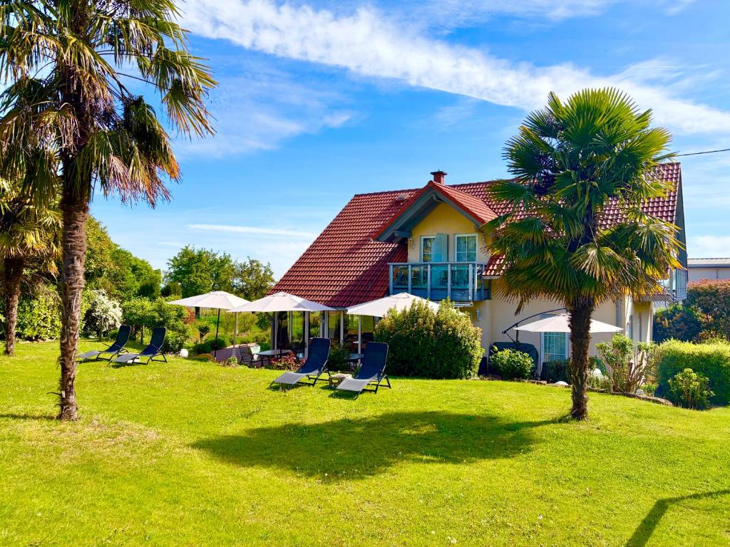 a house with chairs and palm trees in the yard at Gästehaus Helbighof in Neustadt an der Weinstraße
