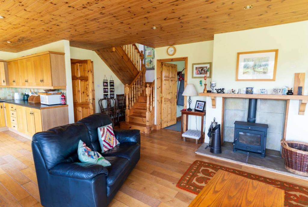 a living room with a leather couch and a stove at Lakehouse Waterville in Waterville