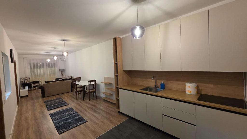 a kitchen with white cabinets and a living room at Art Apartment in Prizren