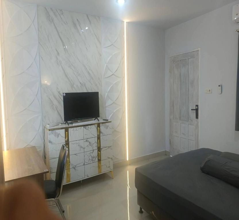 a bedroom with a bed and a desk with a laptop at Cozzy Aryaputra Residence in Gorontalo