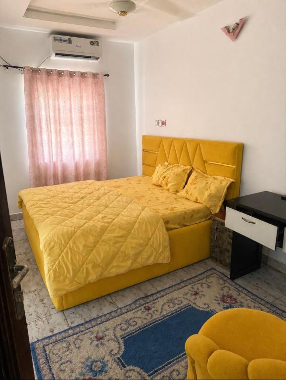 a bedroom with a yellow bed and a desk at Hanover Hotels Suleja in Tunga Bai