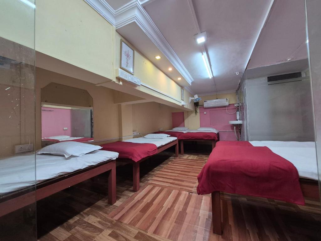 a group of beds in a room with red sheets at Swami Single Bed Dormstay in Ratnagiri