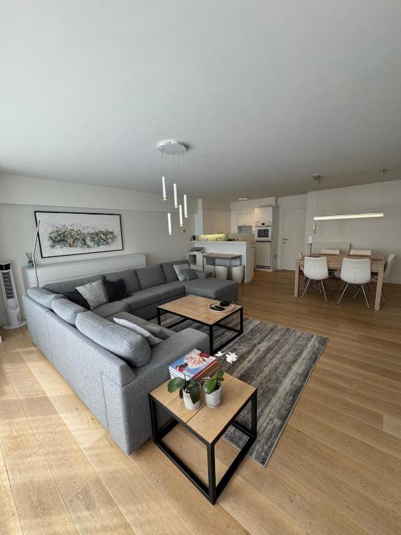 a living room with a gray couch and tables at C-Blanche in Blankenberge