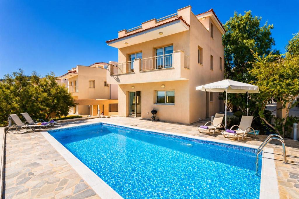 a villa with a swimming pool in front of a house at Villa Panorama Tria in Drousha