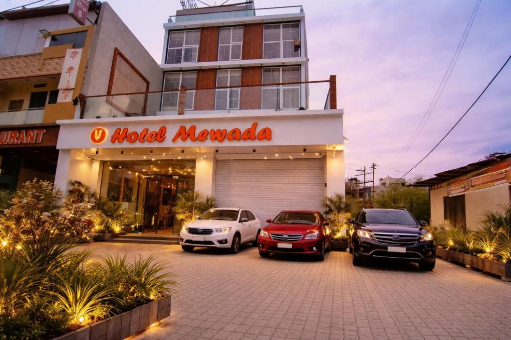 Drei Autos parkten auf einem Parkplatz vor einem Gebäude. in der Unterkunft Hotel Mewada in Ujjain