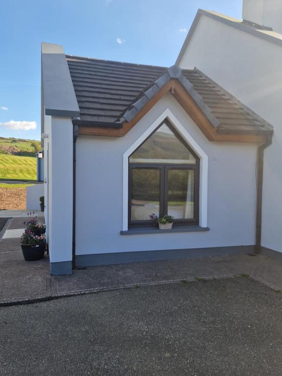 a small white house with a window on it at Dingle Lispole Garden Suite 10 B in Lispole