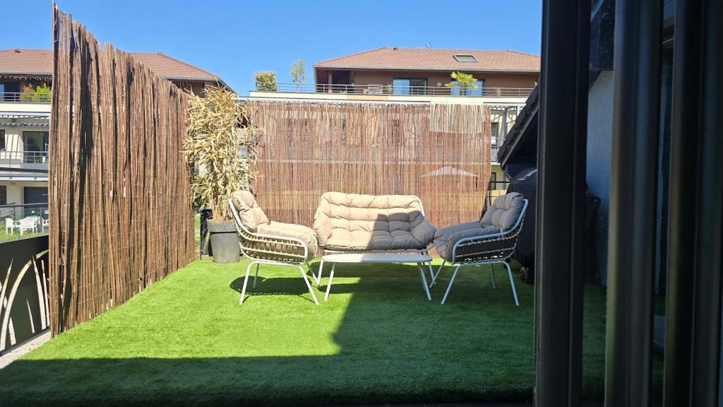 a patio with two chairs and a couch on grass at Maison de village in Copponex