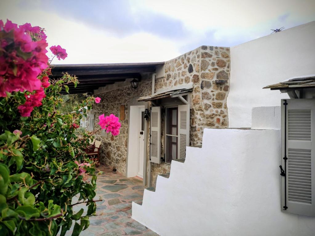 a house with white walls and pink flowers at «Astrofeggia» A private stone house Nature-Seaview in Mandrákion