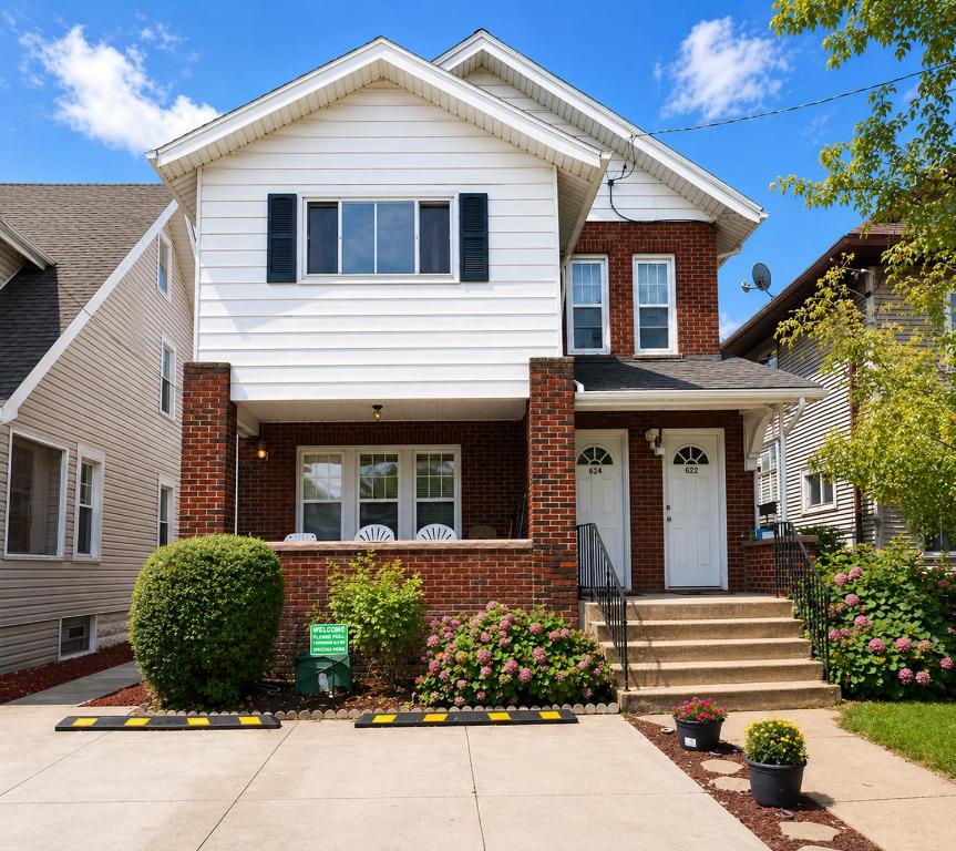 a white house with a brick house at Spacious Frontier Park Apartment in Erie