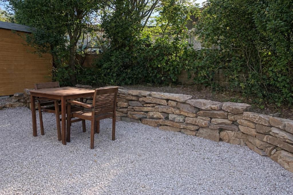 a wooden table with two chairs and a stone wall at L'échappée in Viols-le-Fort
