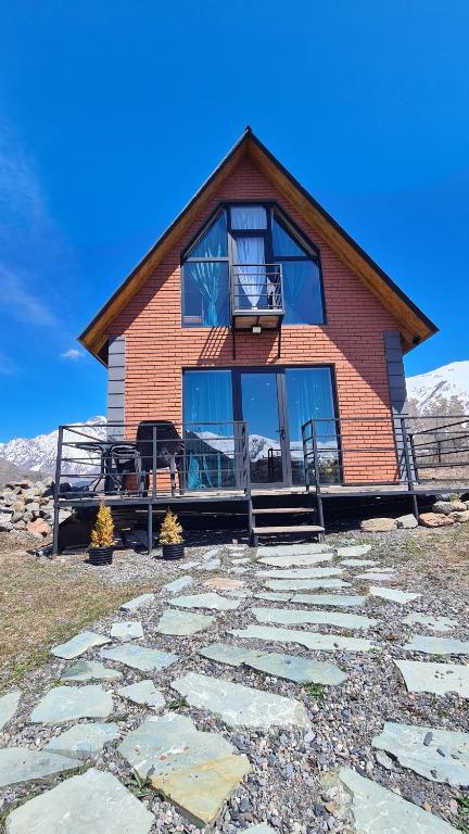 a house with a stone walkway in front of it at Cottage Cozy Yard in Kazbegi