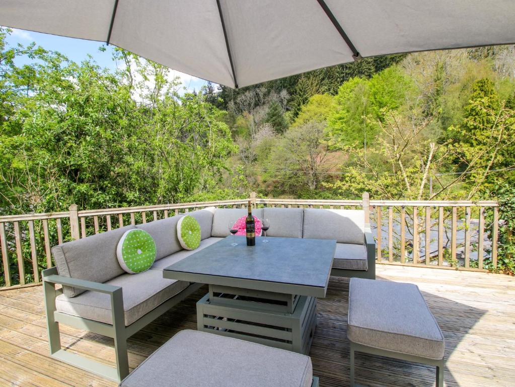 a patio with a couch and a table and an umbrella at Little Pentwyn in Hereford
