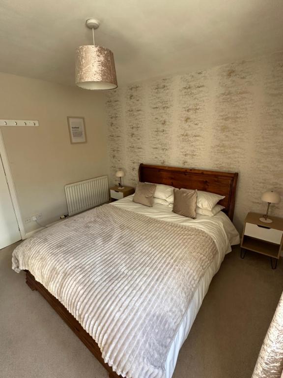 a bedroom with a large bed and two tables at Impala Apartment in Wick