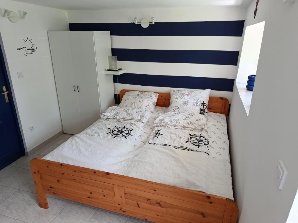 a small bedroom with a bed with white sheets and pillows at Matróz Lak Apartman in Alsóörs