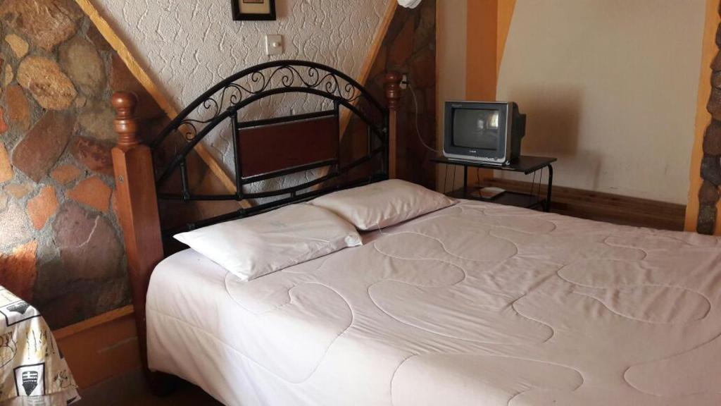een slaapkamer met een bed en een televisie bij Marlin Guest Resort in Nakuru