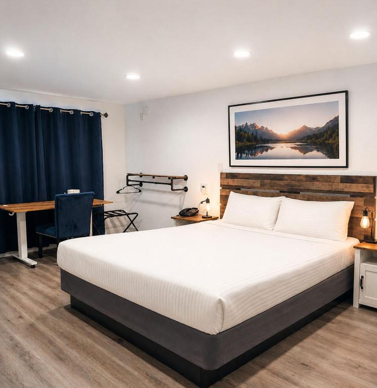 a bedroom with a large white bed and a desk at El Dorado Motel in Twain Harte