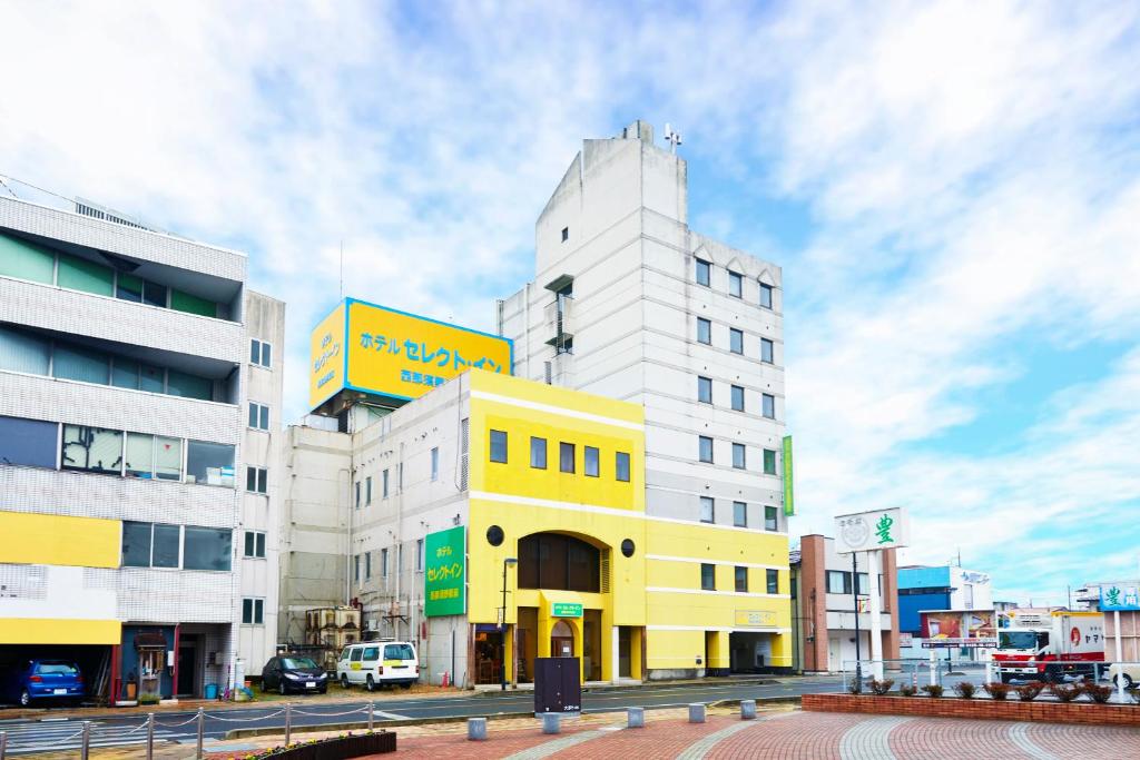 un edificio blanco y amarillo en una calle de la ciudad en Hotel Select Inn Nishinasuno en Nasushiobara