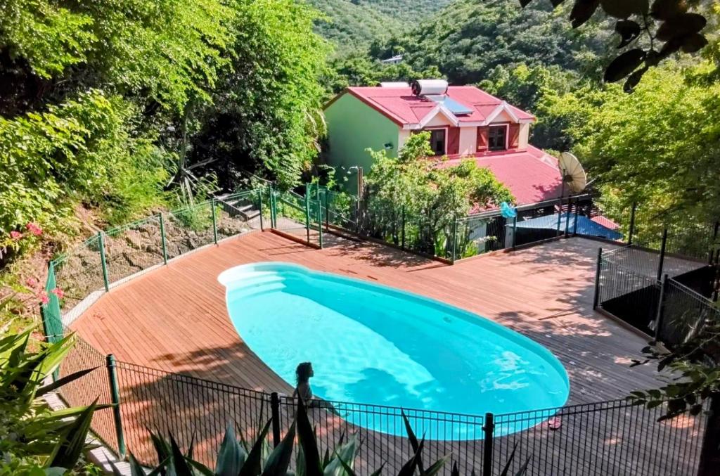 a large swimming pool on a wooden deck with a house at GîteTi Coco de Malendure - Bord de mer - 4 pers in Bouillante