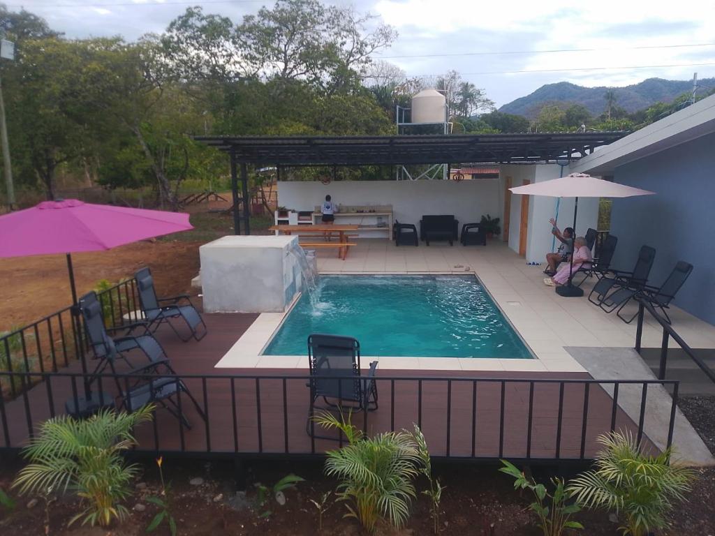 a pool with chairs and a table and an umbrella at Casa Celeste Rio Grande #2 in Puntarenas