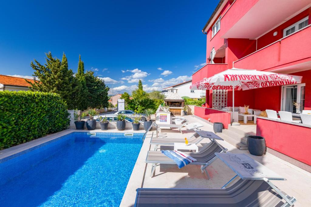 a swimming pool with chairs and an umbrella next to a building at Apartments Mare in Punat