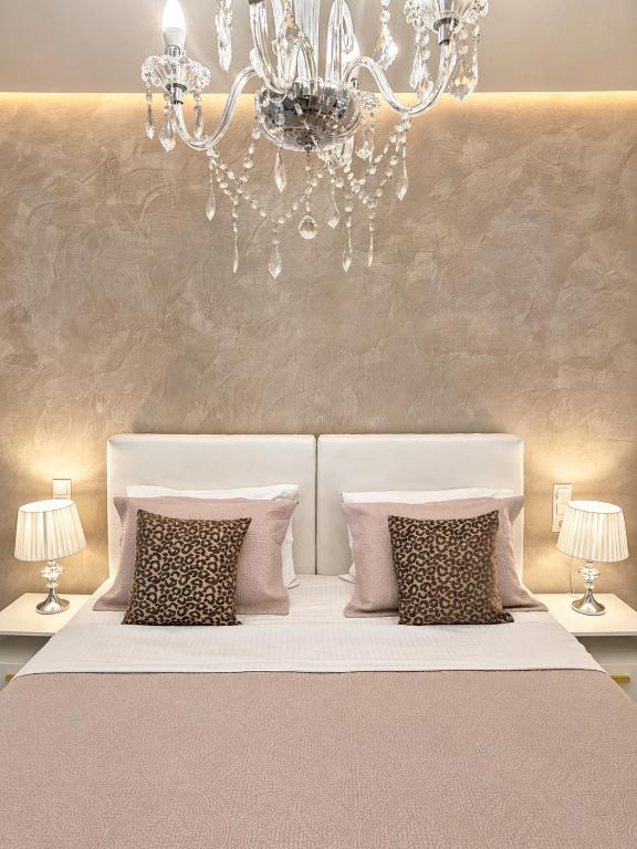 a bedroom with a white bed with pillows and a chandelier at Studios Chrissi-Renovated 2026, Just 20m from the Beach in Skala Sotiros