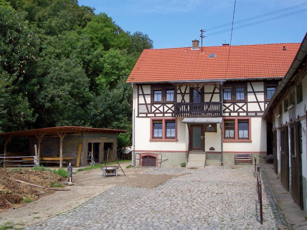 ein altes Haus mit rotem Dach und einem Innenhof in der Unterkunft Pferdehof und Wanderreitstation Dörsam in Mörlenbach