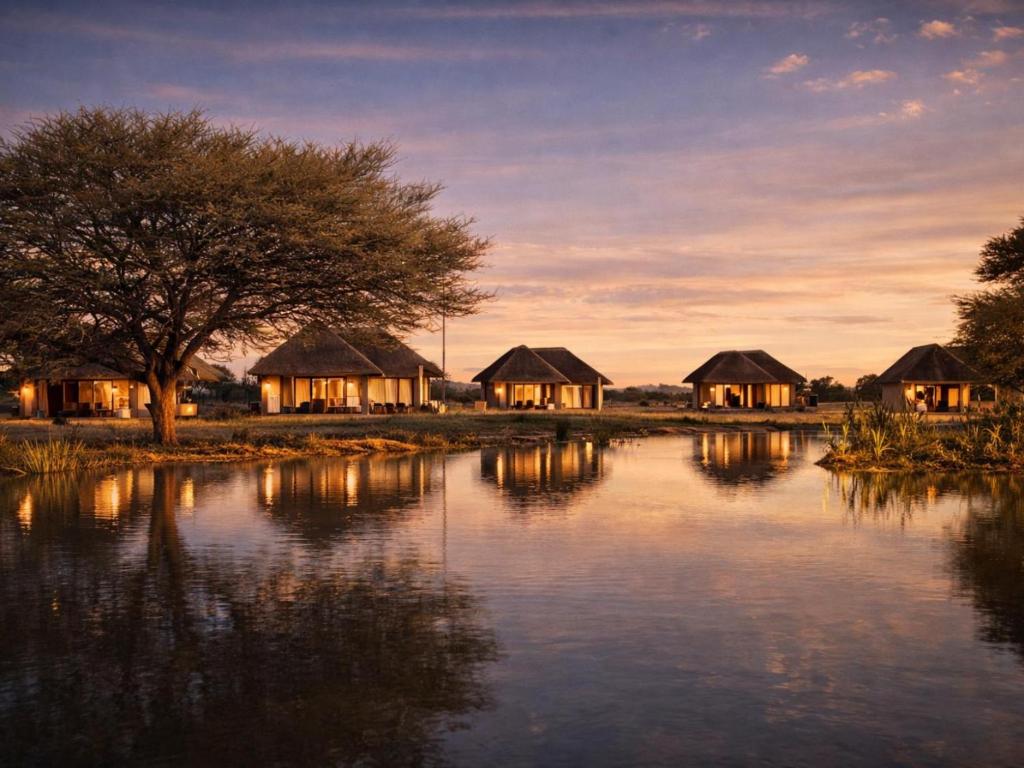 a group of huts next to a body of water at Avenir Safari Group in Okahandja