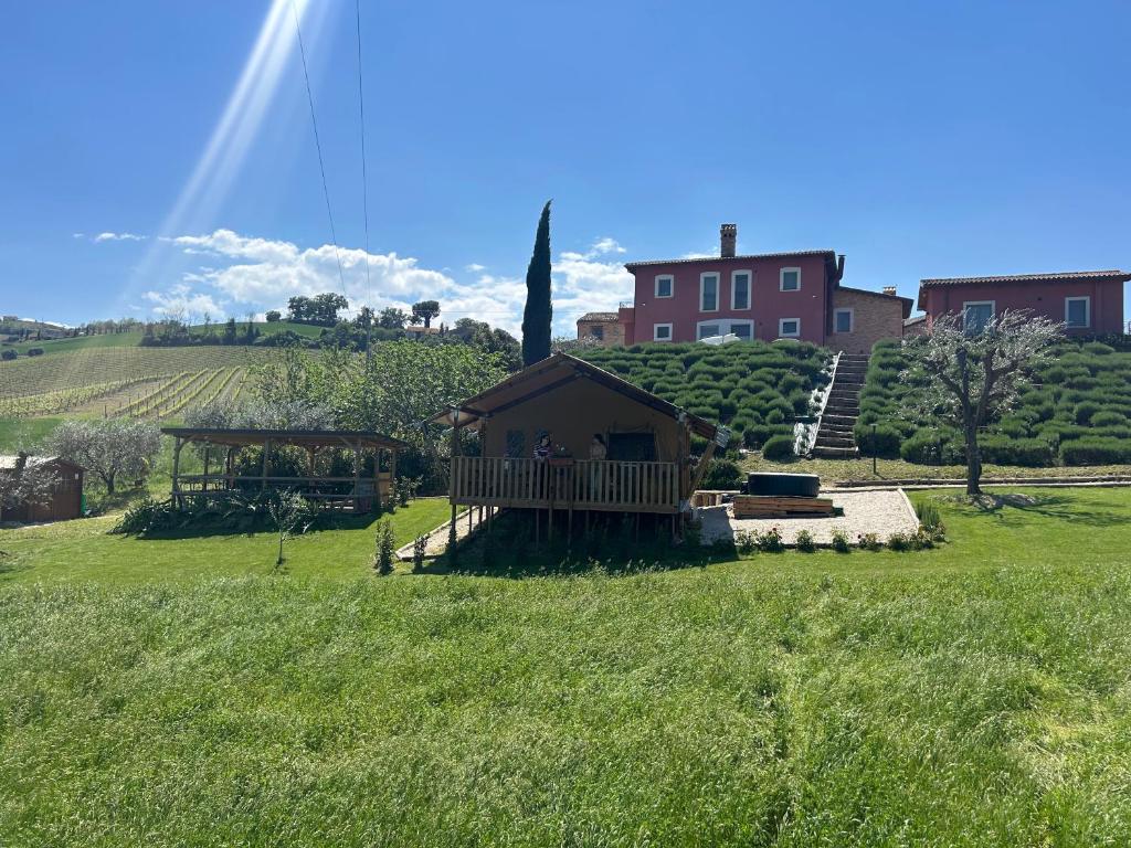 a building in a field with a house in the background at Agriturismo San Filippo Neri in Castignano