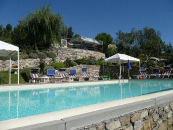 a swimming pool with chairs and umbrellas at San Martino - Casa Landi in Castellina in Chianti