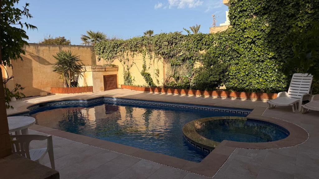 a swimming pool in a yard with two chairs at Stella & Stone Guesthouse in Għarb