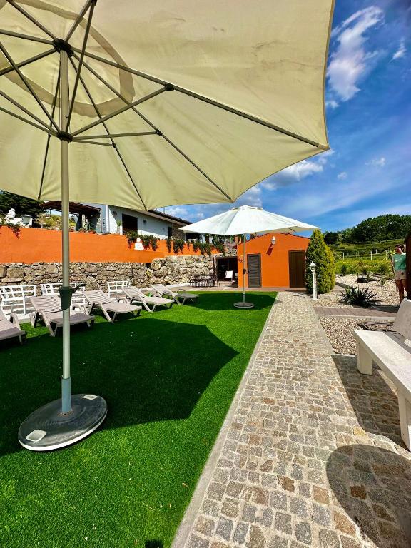 a patio with a large umbrella and white chairs at Quinta Santo Antonio in Gouveia