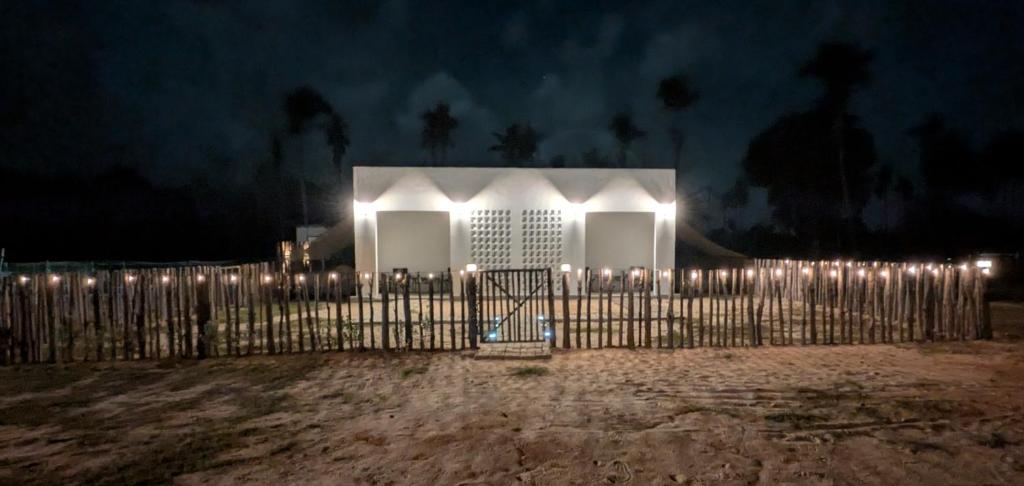 a white house with lights behind a fence at night at Zulis Haven Stay in Kuala Rompin