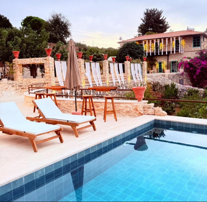 a pool with chairs and a table and a umbrella at Boreas Retreat - Mountain Escape & Spa in Batroûn