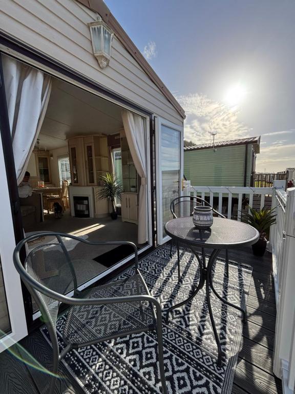 a patio with a table and chairs on a balcony at Welsh Bay Hideaway 2 bed caravan with sun deck in Aberystwyth