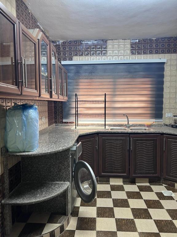 a kitchen with wooden cabinets and a checkered floor at Saeeds apartment in Ajloun