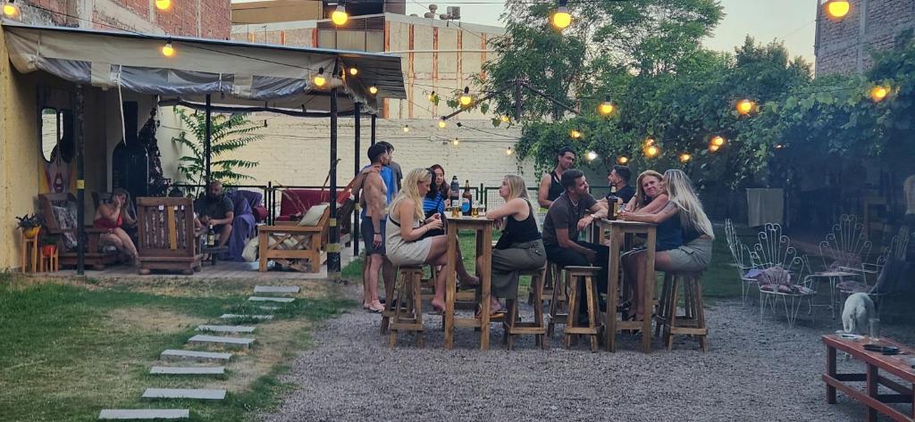 a group of people sitting at tables in a garden at Clover Hostel in Mendoza