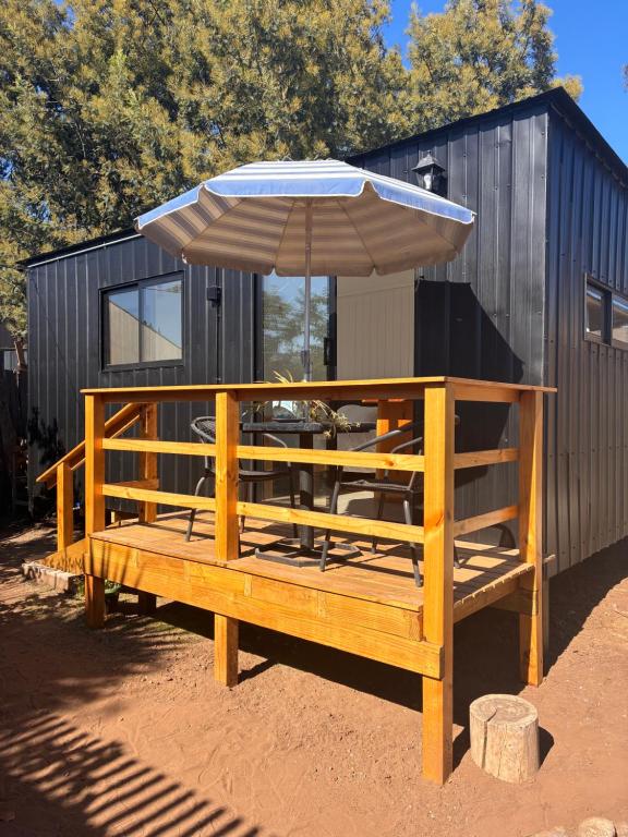 a wooden bench with an umbrella next to a building at La Ola Tiny House in Maitencillo