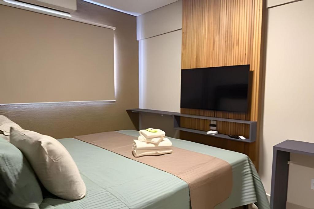 a hotel room with a bed and a flat screen tv at Apartamento - Leblon 409 Conforto & Estilo. in Cuiabá