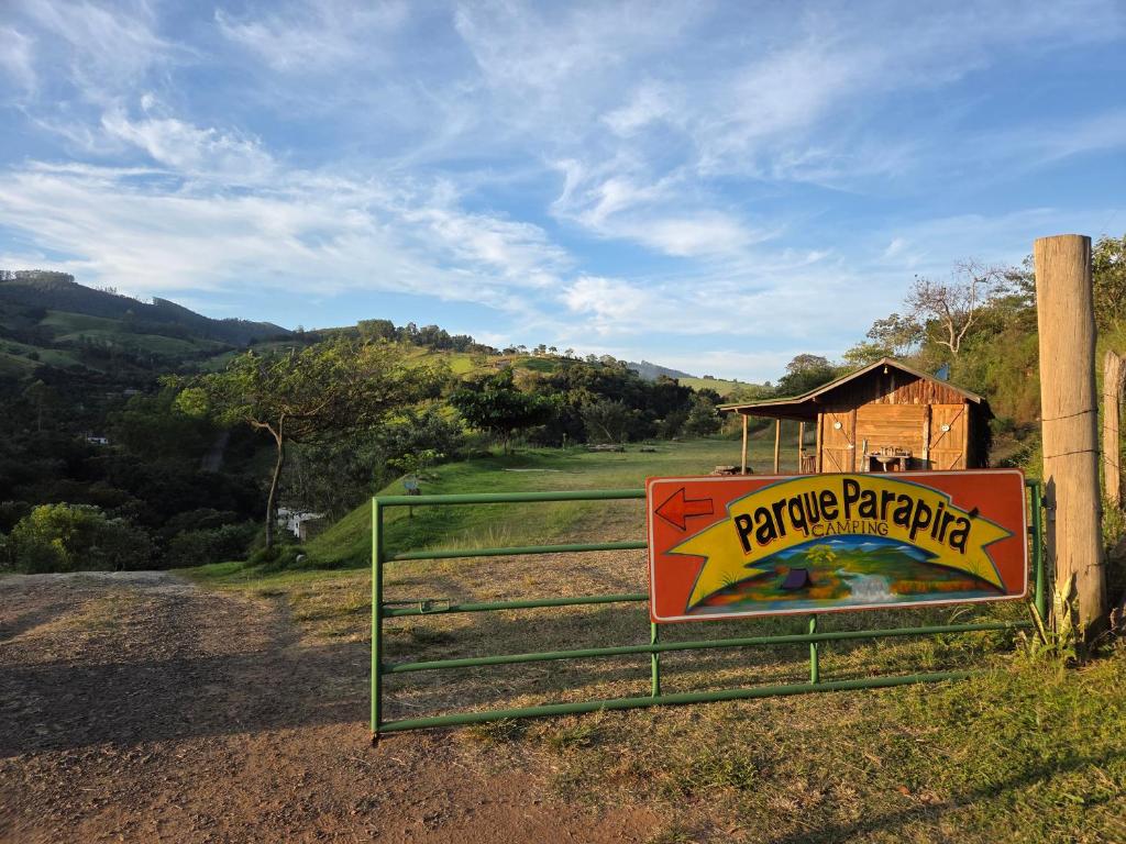 a sign on a gate in a field with a barn at Parque Parapirá Camping in Socorro