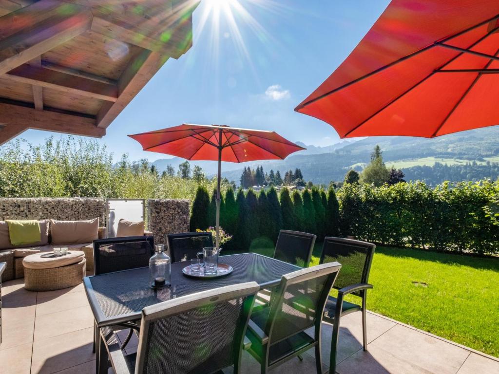 a patio with a table and chairs and red umbrellas at Sonnen Lodge Kaprun in Piesendorf