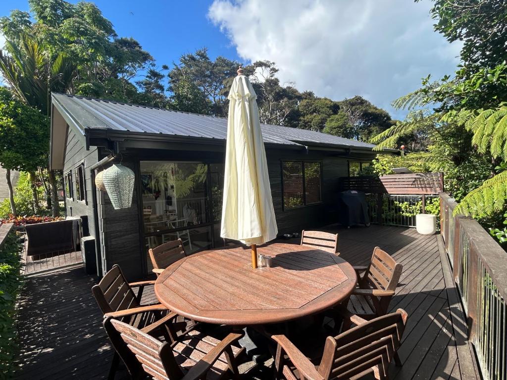 a wooden table with an umbrella on a deck at The Bach at Te Toki in Palm Beach
