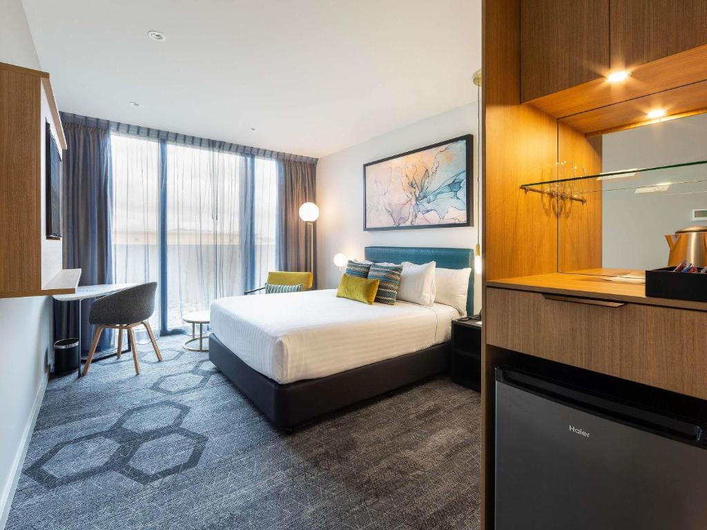 a hotel room with a bed and a desk at Mercure Canberra Belconnen in Canberra