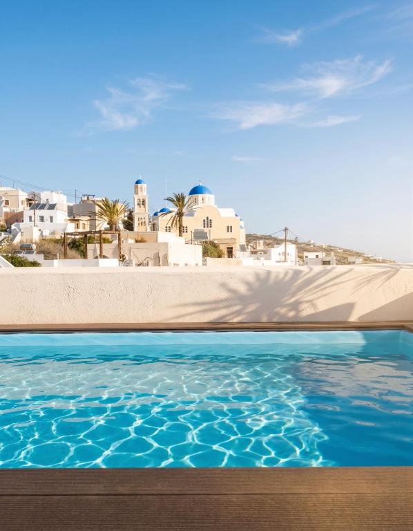 a swimming pool with blue water and buildings in the background at Amaryllis Suites Santorini in Fira
