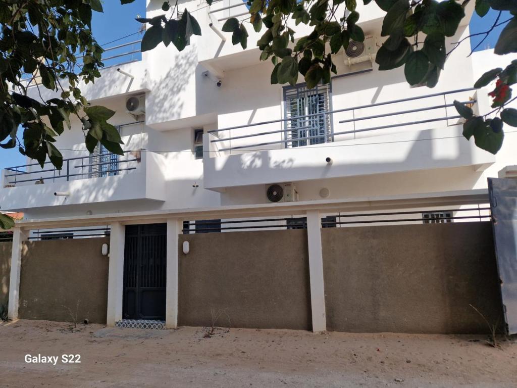 a white building with a gate and a balcony at VILLA KEUR BAYE FALL Saly in Sali Nianiaral